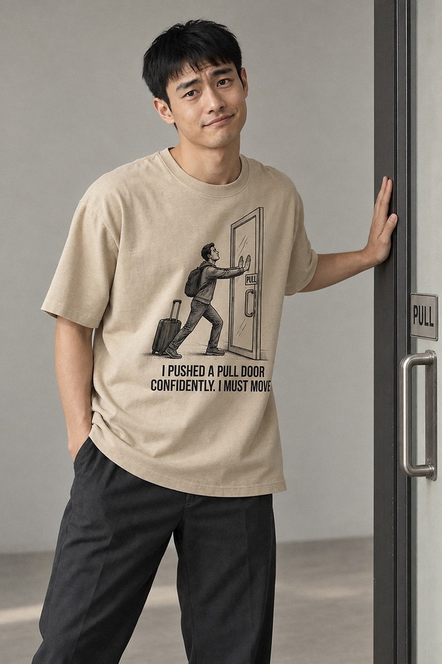 The shirt worn in a studio, palm against a doorframe, caught out